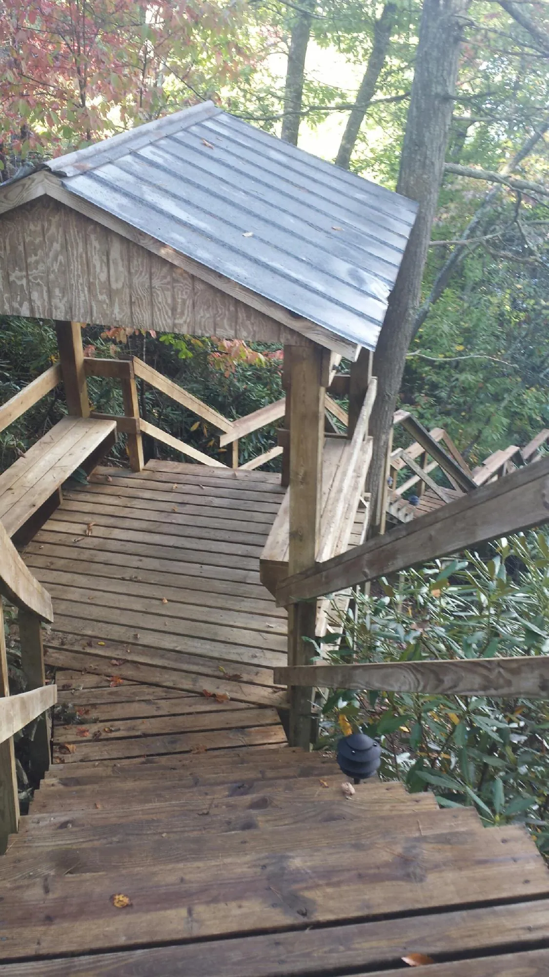 Metal roofed shelter over wooden steps on a wooded walkway — Skylight Repair & Installation work by our crew in Culver