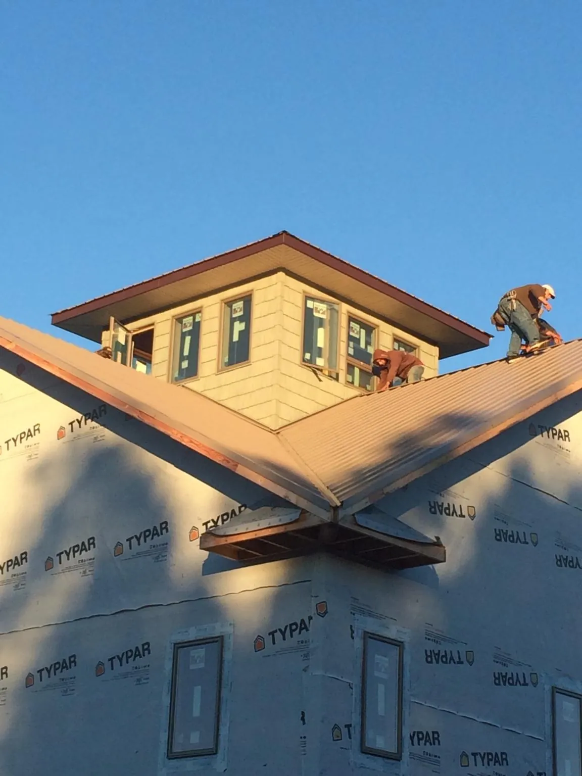 Roofers working around a rooftop cupola on a new metal roof at sunset — Roof Waterproofing in Culver by Roofing Brothers